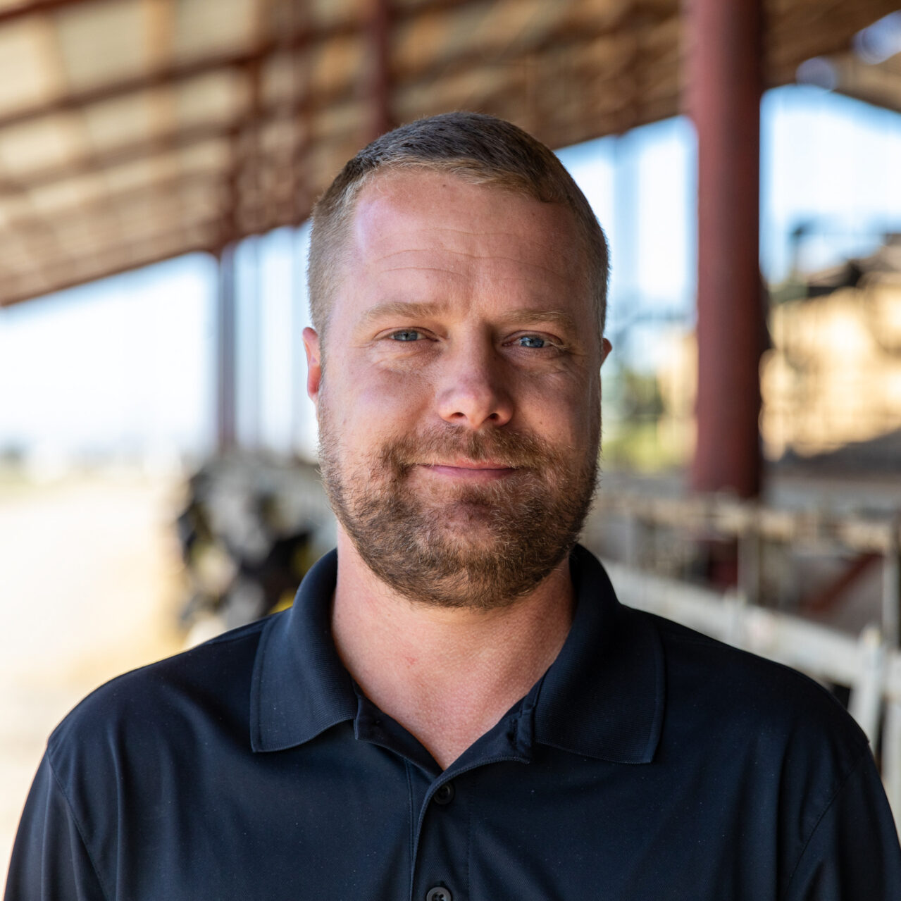Jake Dewitt standing inside a dairy barn with a blurred background.