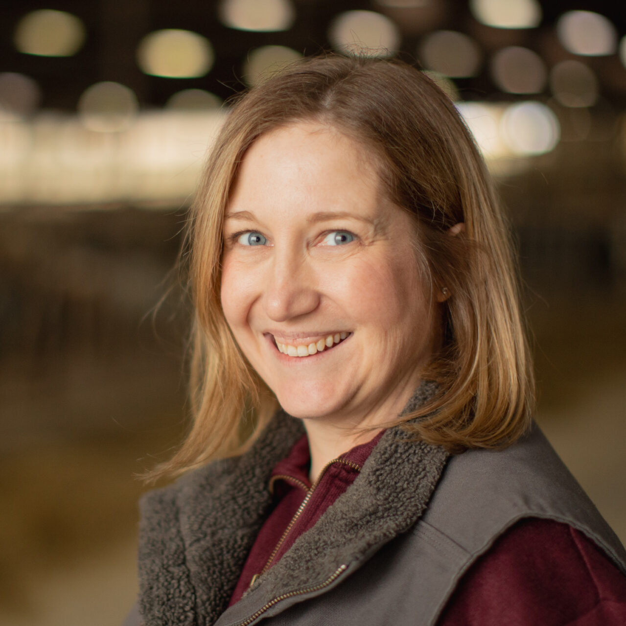 Morgan Harris standing inside a dairy barn with a blurred background.