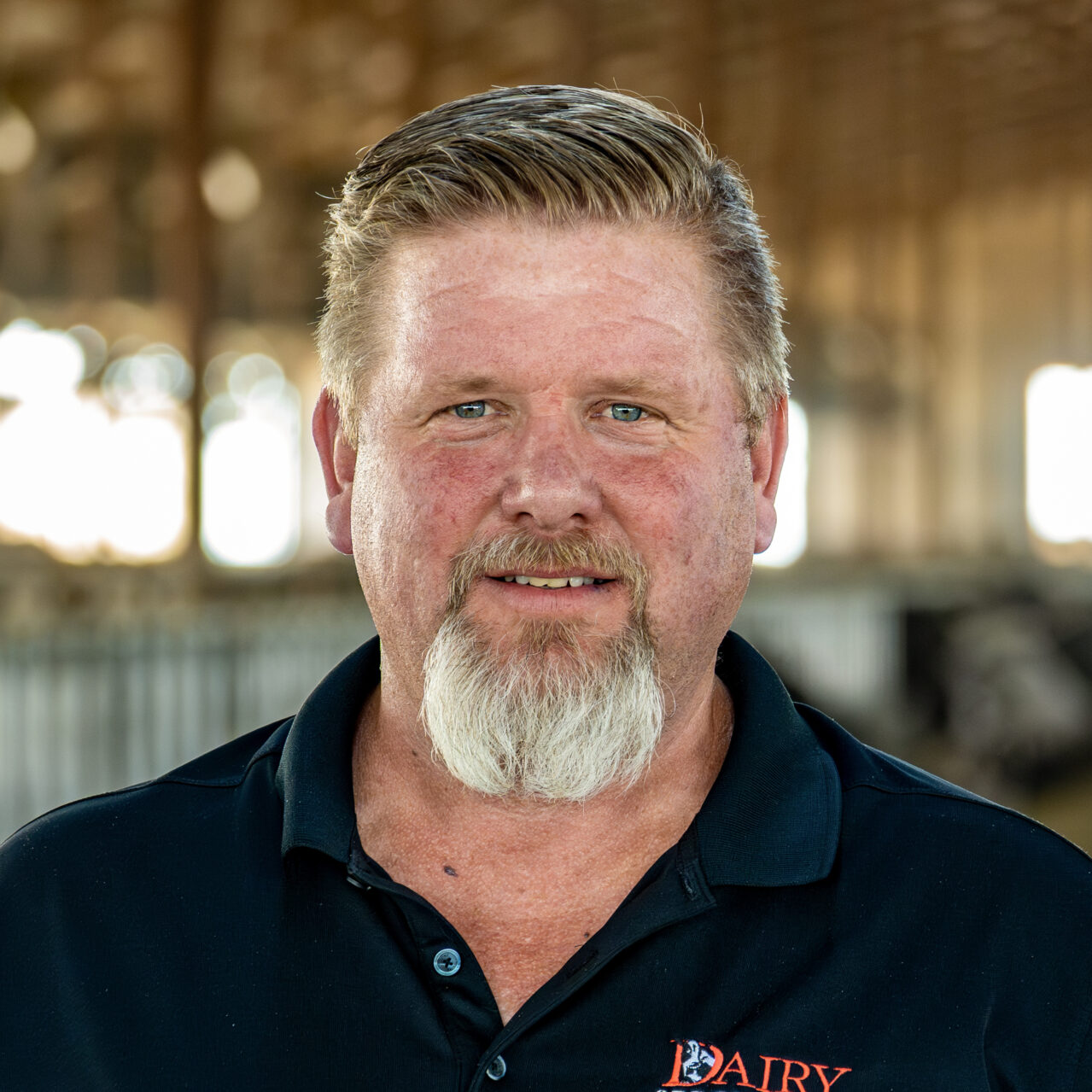 Paul Houweling standing inside a dairy barn with a blurred background.