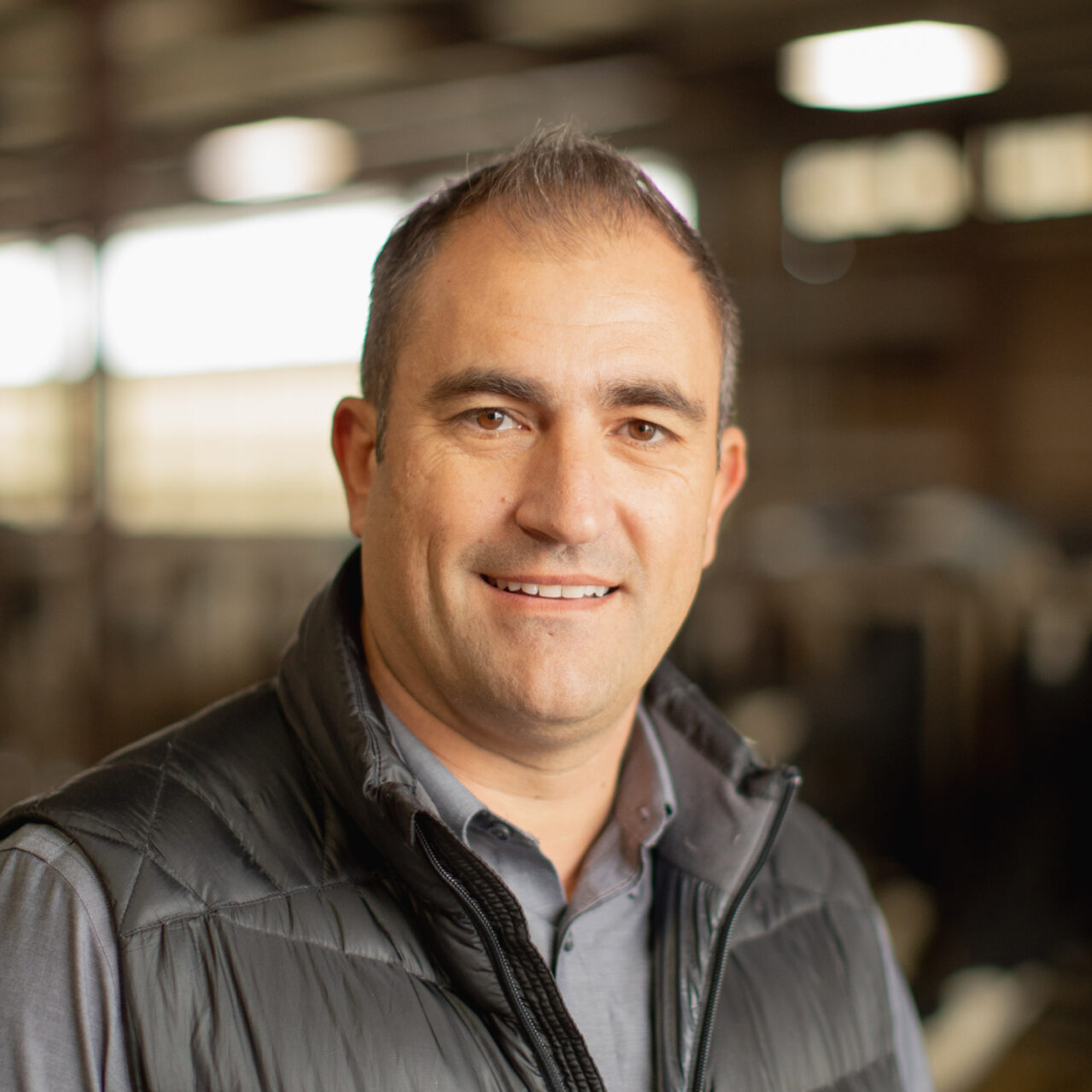 Ryan Calistro standing inside a dairy barn with a blurred background.